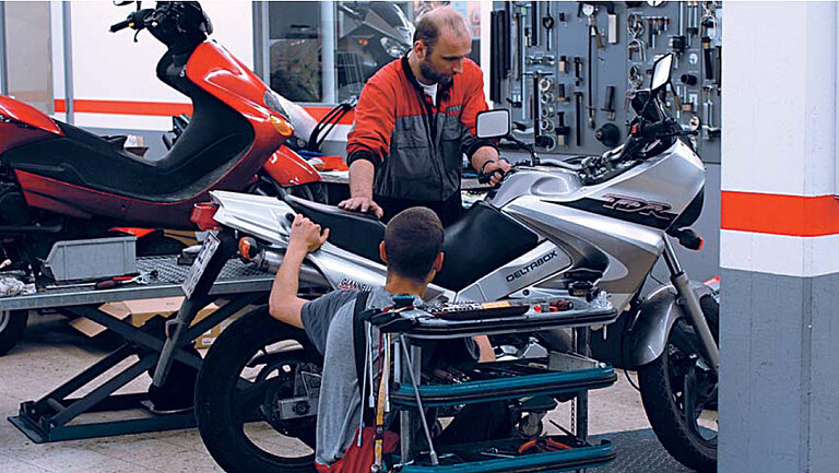 Officina meccanica Foto di un'officina in cui due persone stanno lavorando su una moto.